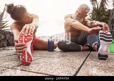 Fitness-Paar, das Dehnübungen im Freien macht - Glückliche Athleten machen eine Trainingseinheit bei Sonnenuntergang draußen Stockfoto