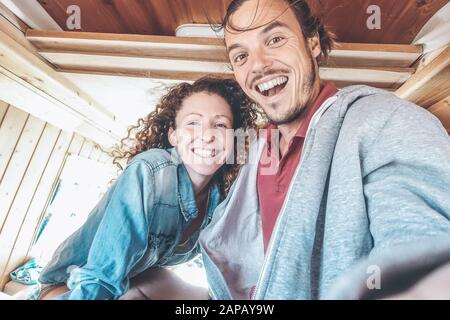 Glückliches Paar, das während einer Roadtrip ein selfie im Mini-Van-Camper macht - Reisen Sie Leute, die Spaß haben, mit dem Handy Fotos im Vintage-Kleinbus zu machen Stockfoto