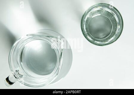 Reine klare Wasser in ein Glas Glas und Glas Krug steht auf einem weißen Hintergrund Stockfoto