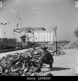 Front North-East Niederlande: Deventer Beschreibung: Auf der IJsselkade verfolgt ein kanadischer Wachmann feindliche Scharfschützen über den Fluss [im Hintergrund die zerstörte Brücke von Deventer] Datum: April 1945 Ort: Deventer, Overijssel Schlüsselwörter: Brücken, Militär Stockfoto
