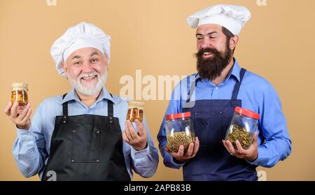 Küchenteam bereitet Essen zu. Familientradition. Koch Männer kochen. Kulinarisches unterrichten. Kulinarisches Rezept. Teamarbeit und Multitasking. Kulinarisches Buch. Reifer bärtiger Mann professionelles Restaurant kocht. Stockfoto