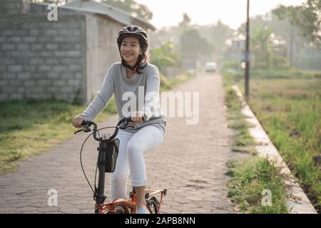 Asiatische Frauen tragen Helme, um mit Klapprädern zu fahren Stockfoto