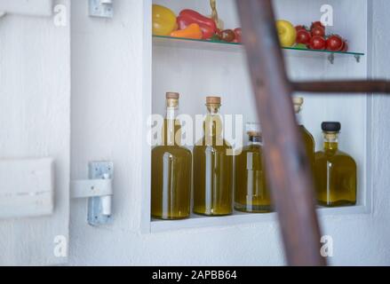 Detailreichtum aus einem Wandregal im Landhausstil Sommer in spanien.Flaschen Öl Gemüse Paprika Pfeffer Zitronentomaten verschwommen diffus Stockfoto