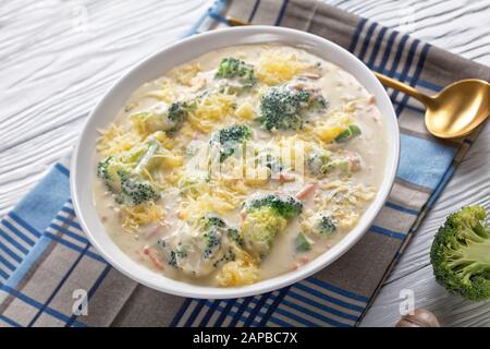 Ketzige Brokkoli und Gemüsesuppe in einer weißen Schüssel mit goldenem Löffel auf einer Serviette, Blick von oben Stockfoto