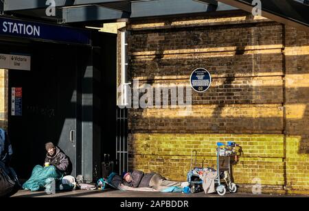 London 21. Dezember 2020: Alter Obdachloser schläft mit seinen persönlichen Sachen ein junger Mann zeigt trotz eines Mi ein Zeichen, das um Hilfe bittet Stockfoto