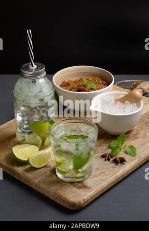 Cachaca caipirinha mit Kalk und gehacktem Eis, Platz zum Kopieren, dunkelbrauner Zucker und frischer Minze, vertikale Zusammensetzung Stockfoto