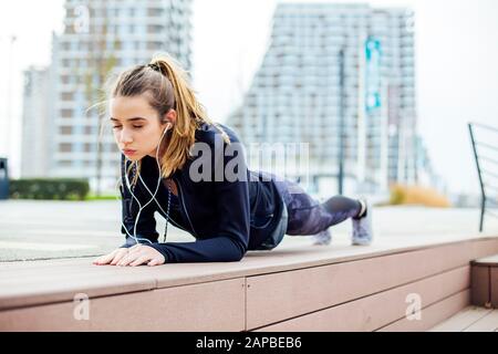 Passen junge Frau tun plank Übung im Freien in der städtischen Umwelt Stockfoto