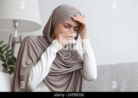 Kranke muslimische Frau in Hijab mit runder Nase und Kopfschmerzen Stockfoto