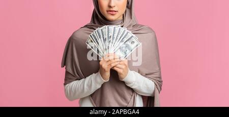 Zweifelhafte arabische Frau, die viel Dollargeld in Händen hält Stockfoto