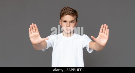 Teenager, der eine Stopp-Geste über grauem Hintergrund macht Stockfoto