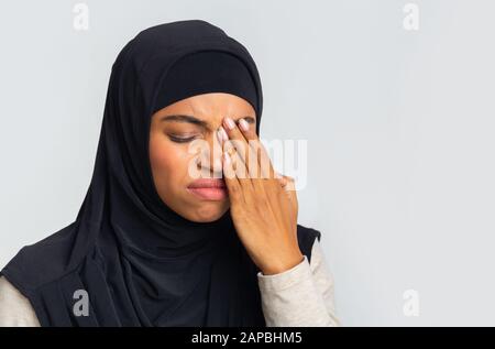 Schwarzes muslimisches Mädchen im Hijab, das unter Augenschmerzen leidet und Augenlid berührt Stockfoto