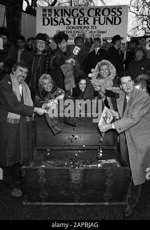 Zeigen Sie Business-Stars, die dabei helfen, die Kassen des Kings Cross Disaster Fund bei einer Karol-Singsitzung am Leicester Square in London zu füllen. (Vorne, L-R) Terry Jones, Judith Chalmers, Sarah Pickering, Billie Whitelaw und Michael Palin. Dahinter steckt die TV-Schauspielerinnen Anna Cateret (mit umkrempeltem Hut) leert ihre Tasche und Emma Thompson hält eine Sammelbox (Mitte), im Hintergrund die Besetzung von "Kiss Me Kate". Stockfoto