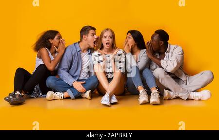 Schockierte Mädchen, die ihren Klassenkameraden zuhören, flüstert Stockfoto