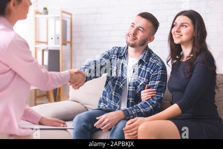 Dankbar paar Handshaking mit Spezialist bei Ratgeber Büro Stockfoto