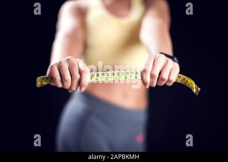 Frau mit kurzen blonden Haaren in Sportkleidung mit Maßband. Fitness-, Diät- und Gesundheitskonzept Stockfoto