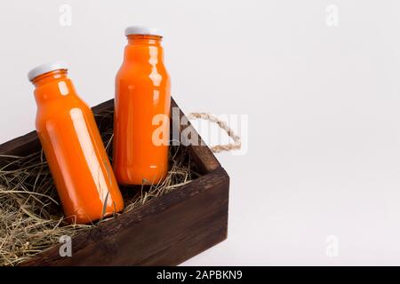 Orangensaft oder Entgiftungsgetränk in einer Glasflasche in der Holzkiste Stockfoto