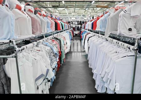 Weiße und helle Frauenshirts hängen an Bügeln und Mannequins in einem Bekleidungs- und Schuhgeschäft. Stockfoto