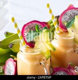 Eine Nahaufnahme von zwei Glasgefäßen tropischer exotischer Fruchtsmoothies, die zum Trinken bereit sind. Stockfoto