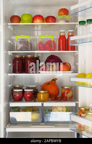 Gläser mit hausgemachtem Obst und Beeren Marmeladen, Säften und frischem Gemüse und Obst im Kühlschrank. Vergorenes, gesundes vegetarisches Essen steht in Kühlschrank Stockfoto