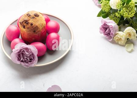 Osterkuchen, naturgefärbte rote Ostereier und Blumen auf Festtagstisch Stockfoto