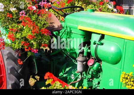 BRÜGGEN, DEUTSCHLAND - 8. AUGUST. 2019: Blick auf grünen Oldtimer-Traktor mit roten, mit Blumen verzierten Rädern Stockfoto