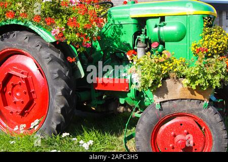 BRÜGGEN, DEUTSCHLAND - 8. AUGUST. 2019: Blick auf grünen Oldtimer-Traktor mit roten, mit Blumen verzierten Rädern Stockfoto
