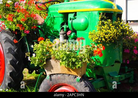 BRÜGGEN, DEUTSCHLAND - 8. AUGUST. 2019: Blick auf grünen Oldtimer-Traktor mit roten, mit Blumen verzierten Rädern Stockfoto