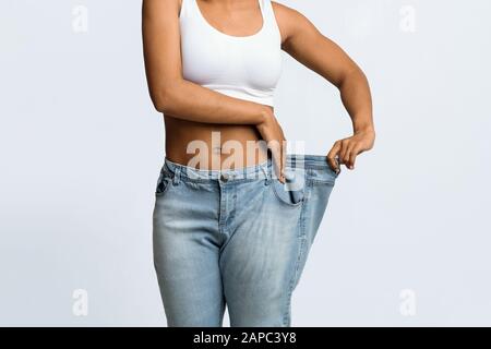 Junge schwarze Frau, die zu große Jeans trägt Stockfoto