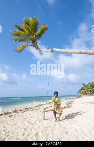 Mittelamerika, Nicaragua. Ein garifuna-musiker in traditioneller Kleidung, der an einem Strand auf Little Corn Island eine Handtrommel spielt Stockfoto