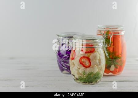 Drei Glasgefäße aus fermentiertem Rotkohl, Blumenkohl, Karotten, Gemüse mit leichtem Hintergrund. Fermentation ist eine Quelle für Probiotika Stockfoto