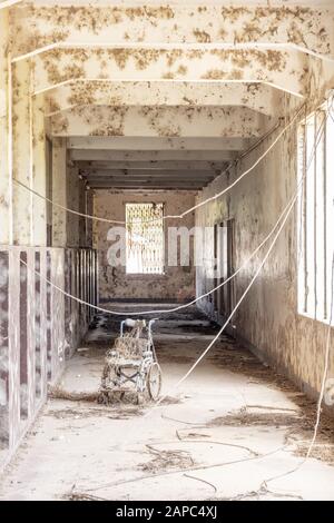 Rollstuhl im Korridor eines verlassenen Krankenhauses oder einer Schule Stockfoto