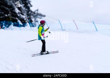 Fernsicht der Frau, die während des Skis das Smartphone überprüft Stockfoto