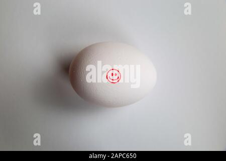 Nehmen Sie es einfach und halten Sie es einfach: Ikone des roten fröhlichen lächelnden Gesichts auf isoliertem Ei mit weißem Hintergrund Stockfoto