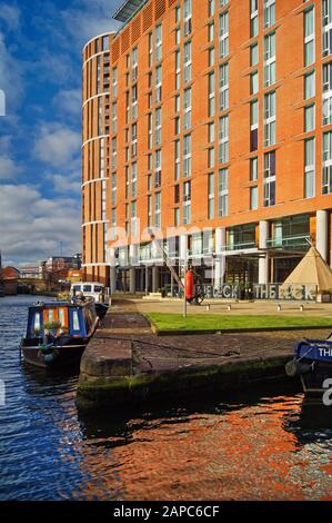 Großbritannien, West Yorkshire, Leeds, Granary Wharf und River Aire. Die Gebäude sind Candle House und Hilton Hotel Stockfoto