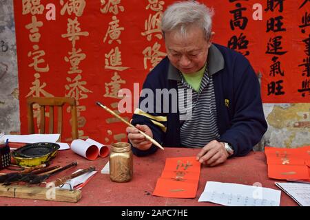 Foshan, CHINA - CIRCA JANUAR 2020: Ein Mann, der während des Frühlingsfestes segnende Paare schreibt. Eine Übersetzung von Couplets ist Ein Glückliches und prosperendes Jahr Stockfoto