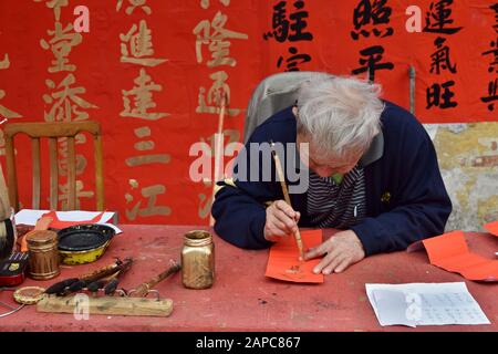 Foshan, CHINA - CIRCA JANUAR 2020: Ein Mann, der während des Frühlingsfestes segnende Paare schreibt. Eine Übersetzung von Couplets ist Ein Glückliches und prosperendes Jahr Stockfoto