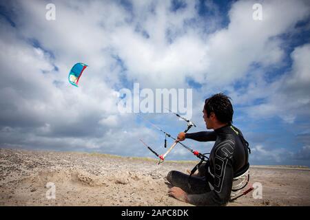 Ein Mann, der sich auf das Kitesurfen am Strand der Nordsee in Dänemark vorbereitet, hält Kite Surfer an der Steuerbar Stockfoto