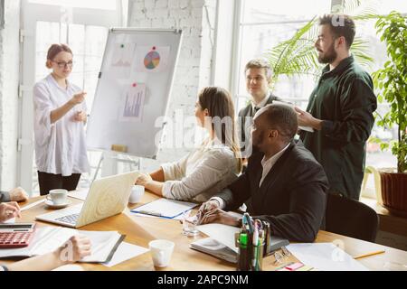 Für Ideen. Gruppe junger Geschäftsleute, die ein Treffen haben. Verschiedene Mitarbeitergruppen diskutieren neue Entscheidungen, Pläne, Ergebnisse und Strategien. Kreativität, Arbeitsplatz, Wirtschaft, Finanzen, Teamarbeit. Stockfoto