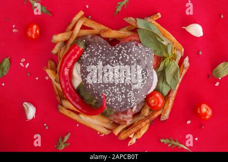 Herzförmige schwarz Hamburger und Pommes Frites, liebe Burger fast food Konzept, Valentinstag Überraschung zum Abendessen, Holz- Hintergrund, Ansicht von oben flach Stockfoto