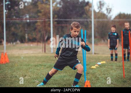 Fußball-Bohrer: Der Slalom Bohren. Jugend-fußball-Übungen. Jungen Fußball-Training der Tonhöhe. Fußball slalom Konus bohren. Junge in Fußball jerse Stockfoto