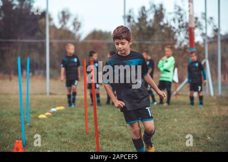 Fußball-Bohrer: Der Slalom Bohren. Jugend-fußball-Übungen. Jungen Fußball-Training der Tonhöhe. Fußball slalom Konus bohren. Junge in Fußball jerse Stockfoto