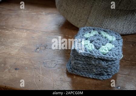 Handgefertigte Häkelgrannenfelder auf Holztisch. Stockfoto