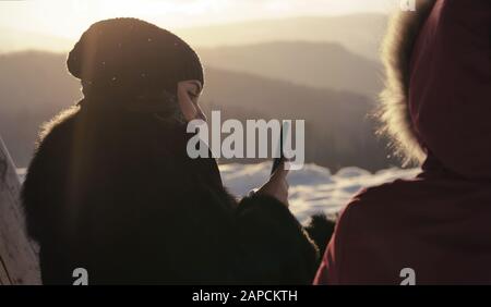 Das Mädchen fotografiert mit ihrem Telefon bei Sonnenuntergang auf den Karpaten Stockfoto