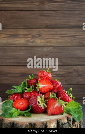 Haufen reifer Erdbeeren auf Holztisch auf verschwommenem Hintergrund. Organische Beeren Schließen Sich. Rotes, saftiges Makrofoto. Selektiver Fokus. Fragaria. Reich an V Stockfoto