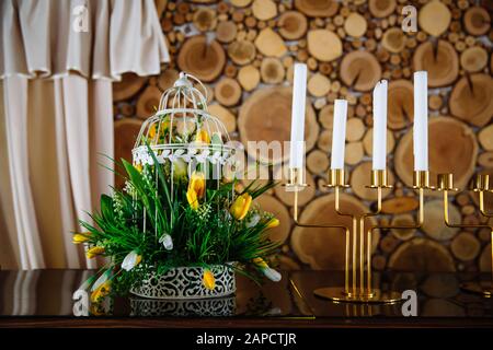 Goldene Kerzenhalter mit Kerzen und Blumen schön auf einen Esstisch gelegt. Stockfoto