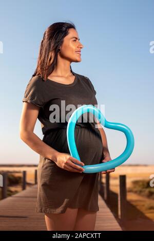 Schwangere Frau posiert mit blauem Herzballon auf den Marschländern. Stockfoto