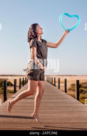 Schwangere Frau posiert mit blauem Herzballon auf den Marschländern. Stockfoto