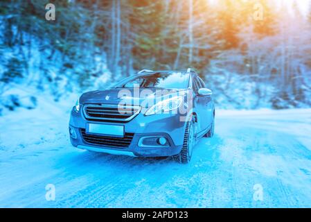 Fahren des Autos auf der eisigen Straße. Blick auf das Auto von vorne. Wald im Hintergrund Stockfoto
