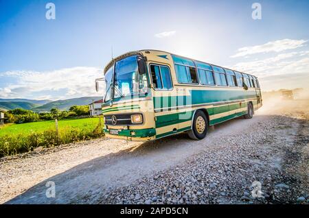 Berat, Albanien - 31. Juli 2014. Alter grüner Bus auf der Feldstraße bei Sonnenuntergang Stockfoto