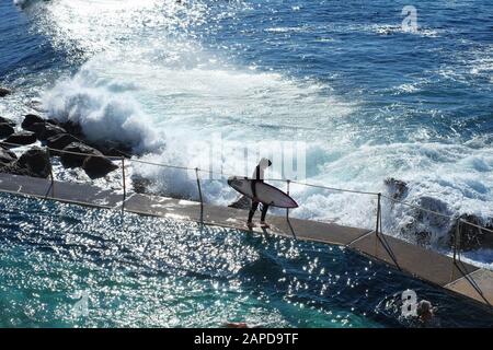 Ein Surfer spaziert am Bronte Ocean Pool, um im Morgenlicht in Sydney, New South Wales, Australien, zu surfen Stockfoto